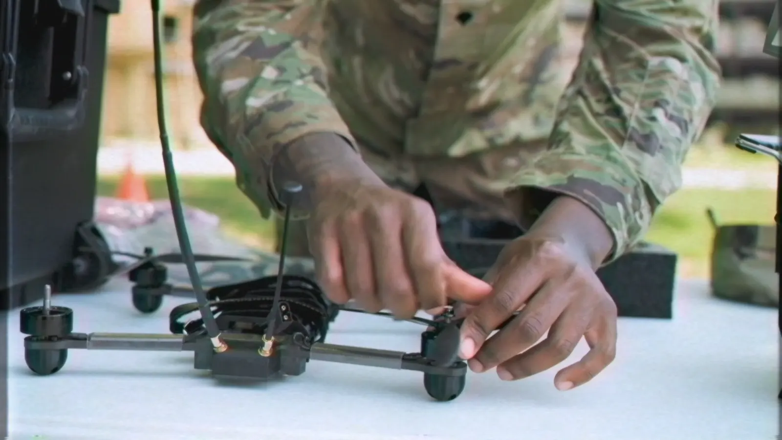 A service member's hands assembling a small drone at a table