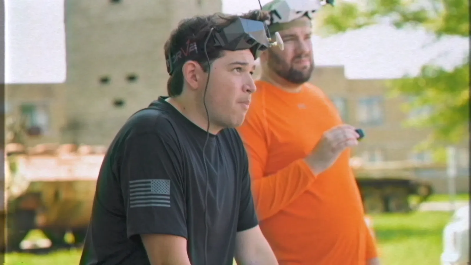 Two pilots flying first-person-view drones outdoors