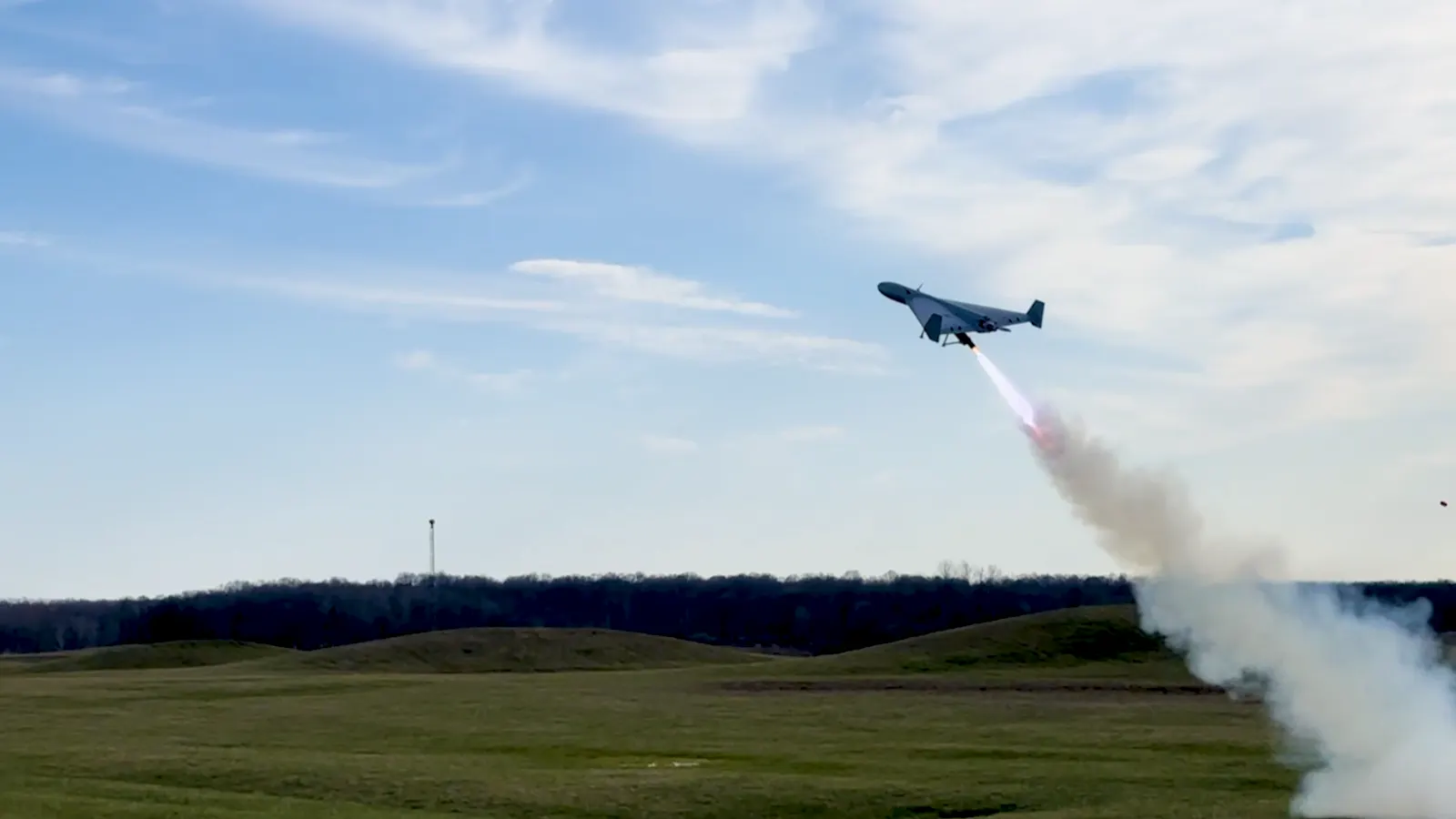 A fixed-wing drone climbing off its launcher with a smoke trail