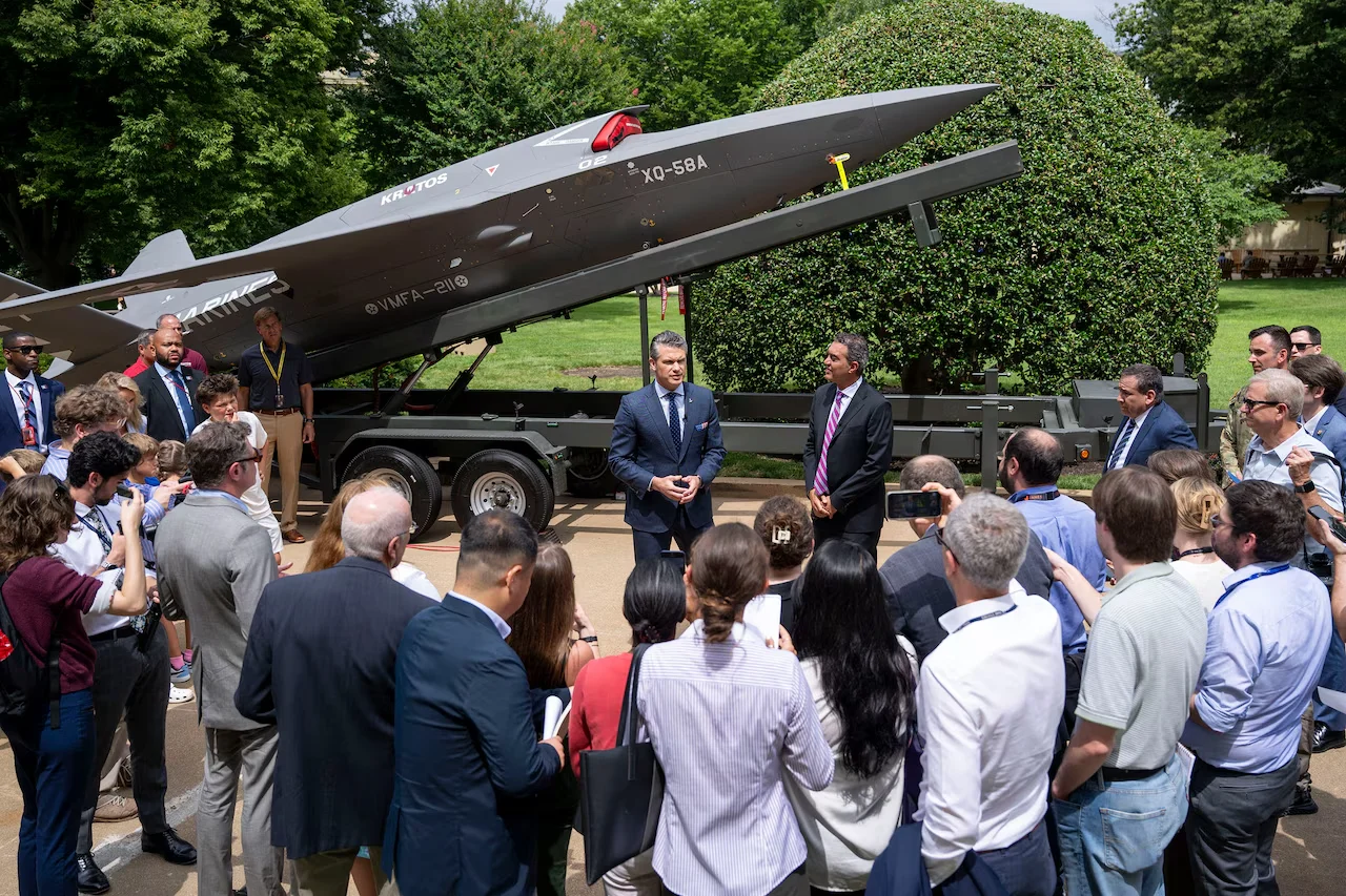 Press and attendees gather around an XQ-58A drone on its launch trailer at the Pentagon